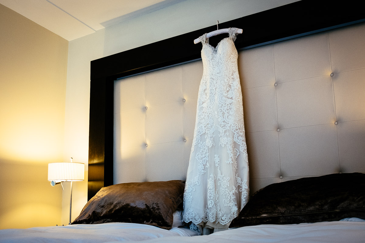 Wedding dress on a hanger against the tufted headboard of the bed at Carton House.