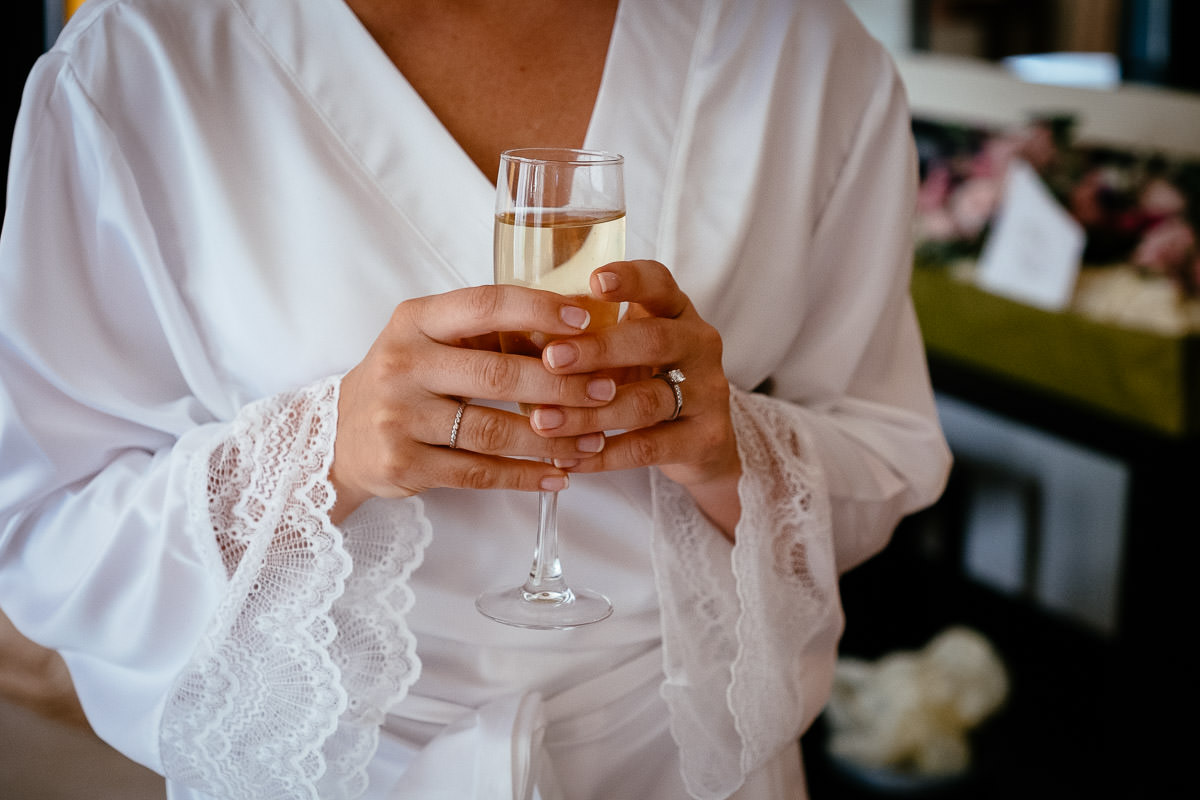 The bride holds a glass of champagne while getting ready at Carton House.