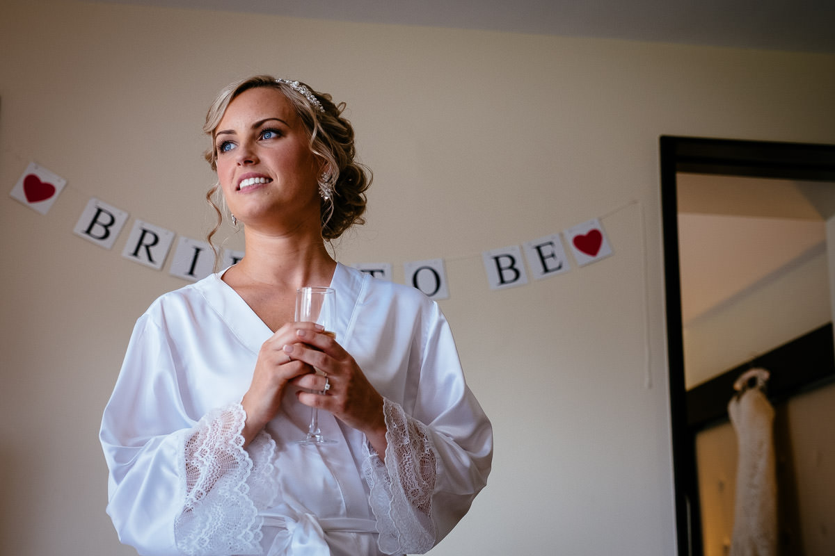 The bride smiles beside a 'Bride to Be' banner while getting ready at Carton House.