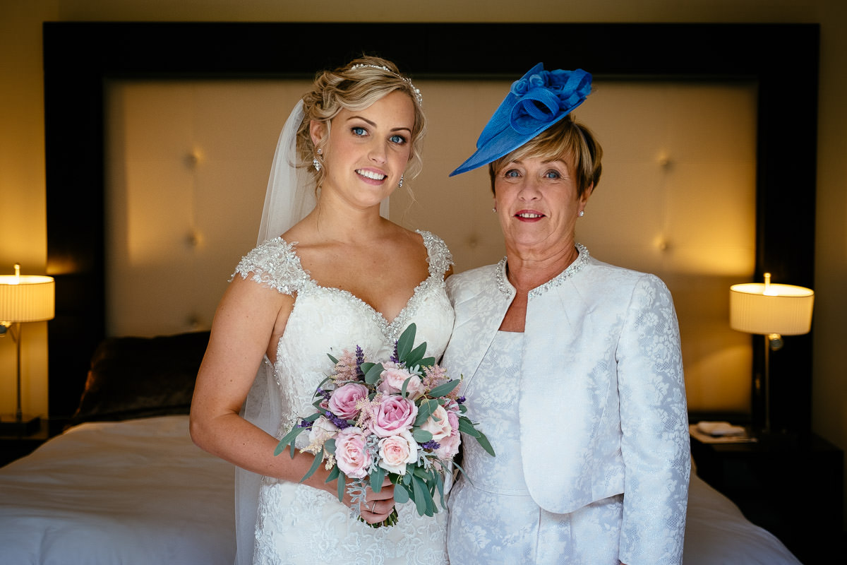 The bride and her mother, wearing a blue fascinator, pose together before the wedding at Carton House.