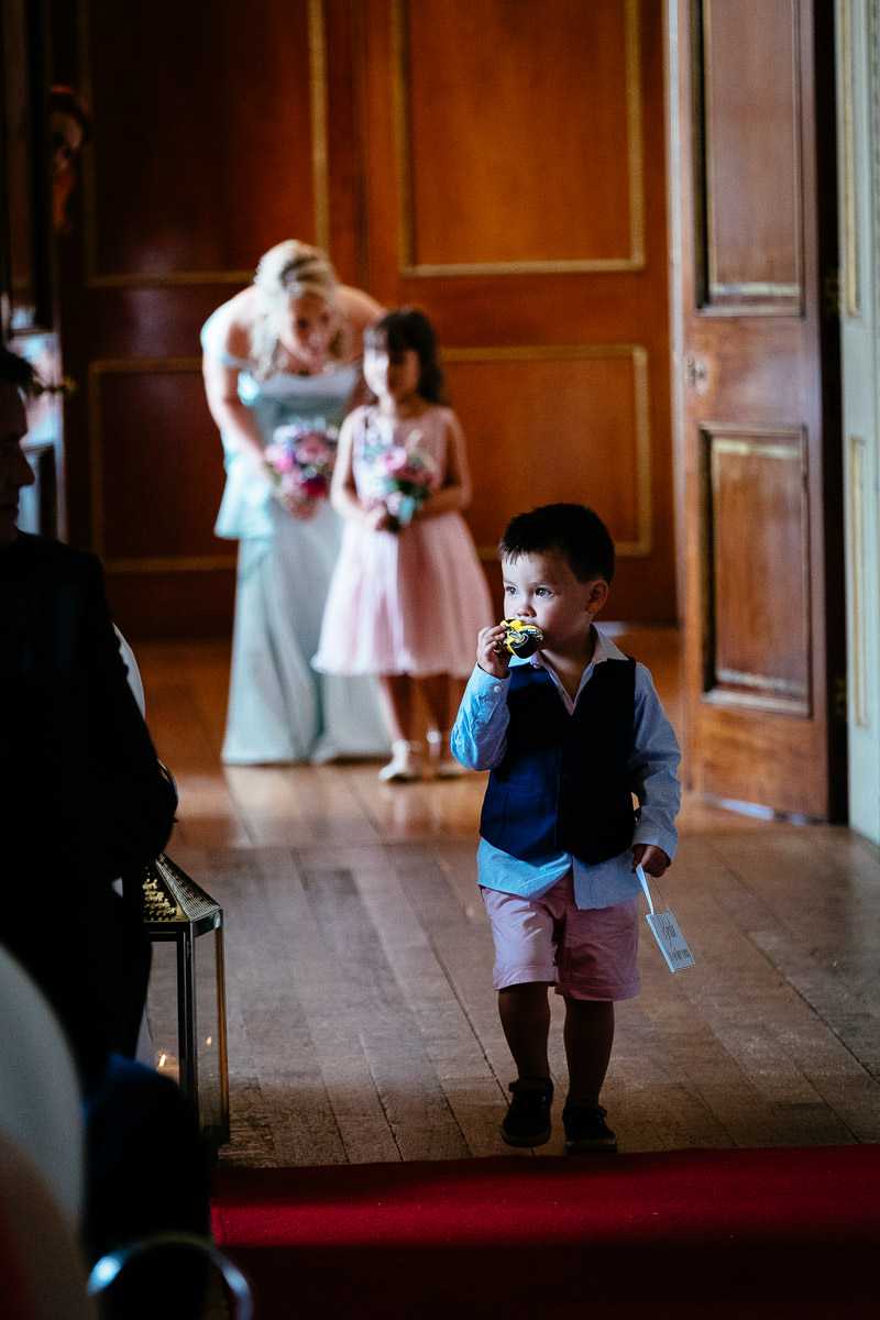 A page boy carrying the rings walks ahead of bridesmaids at Carton House.