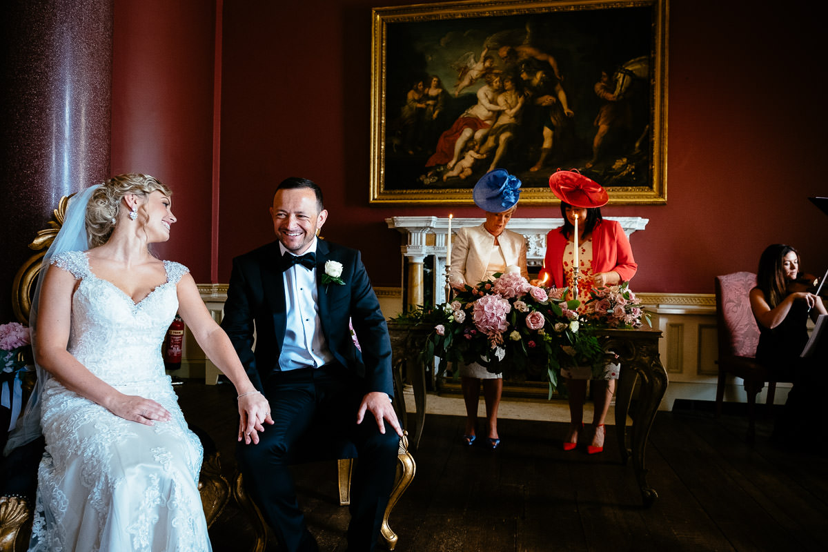 The bride and groom sit together smiling during their ceremony at Carton House.