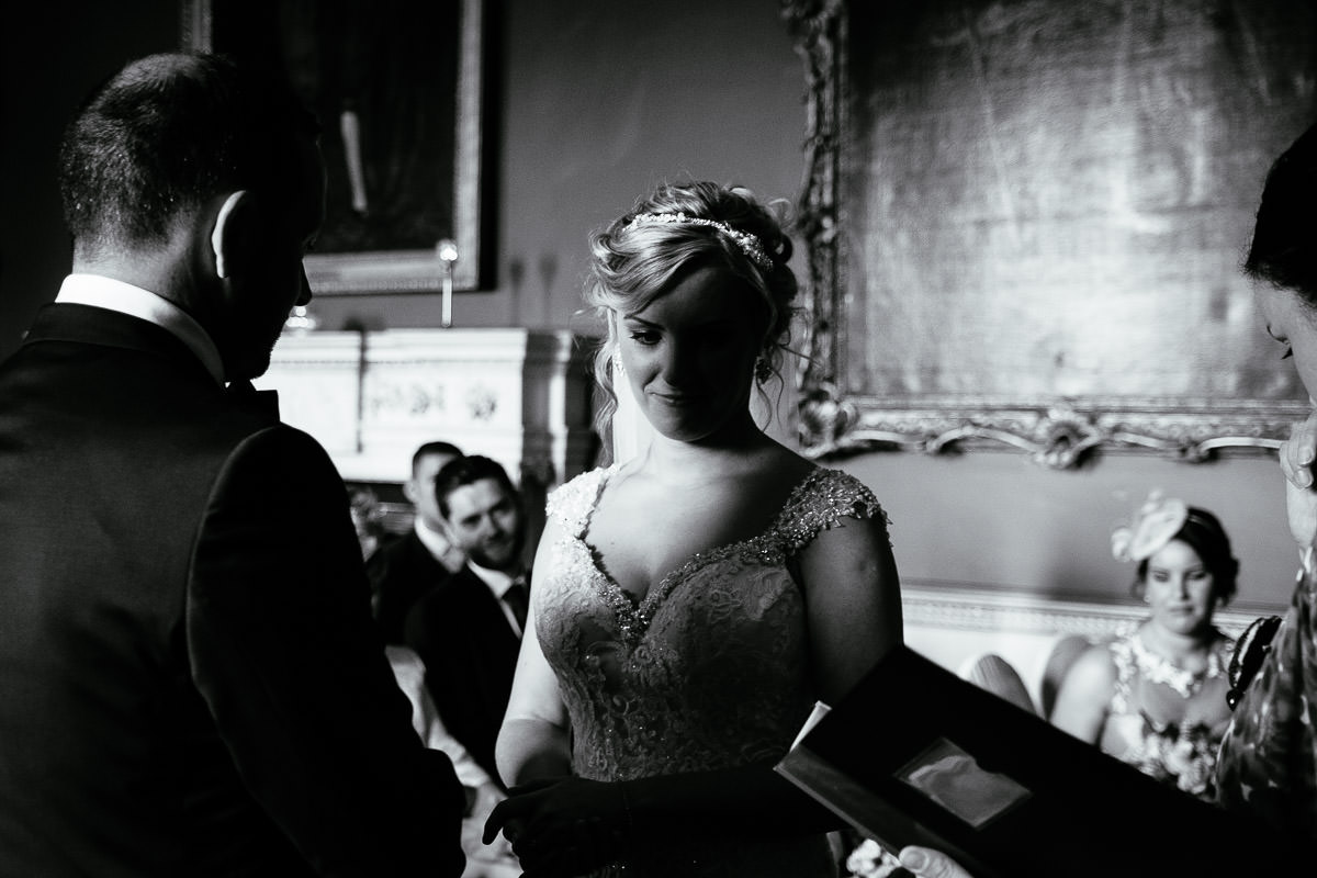 The bride looks down smiling as the groom stands close during their ceremony at Carton House.