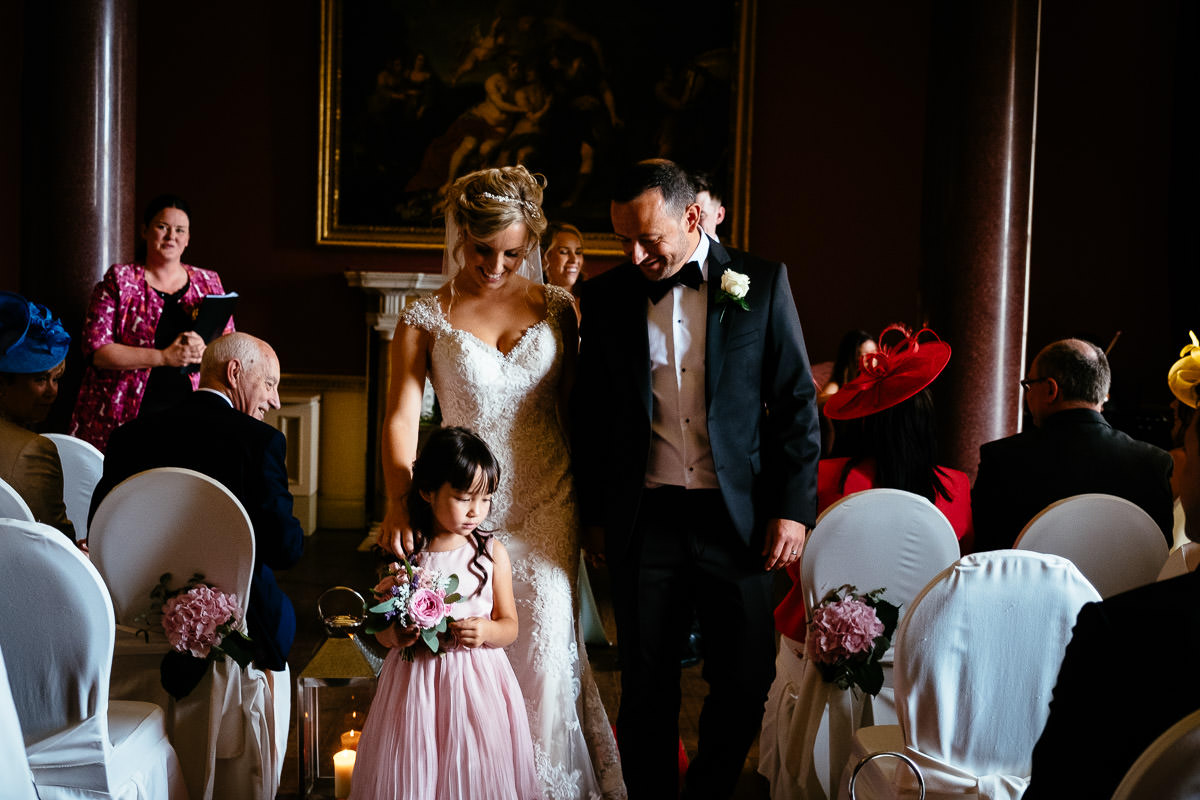 The newlyweds walk back down the aisle with a flower girl at Carton House.
