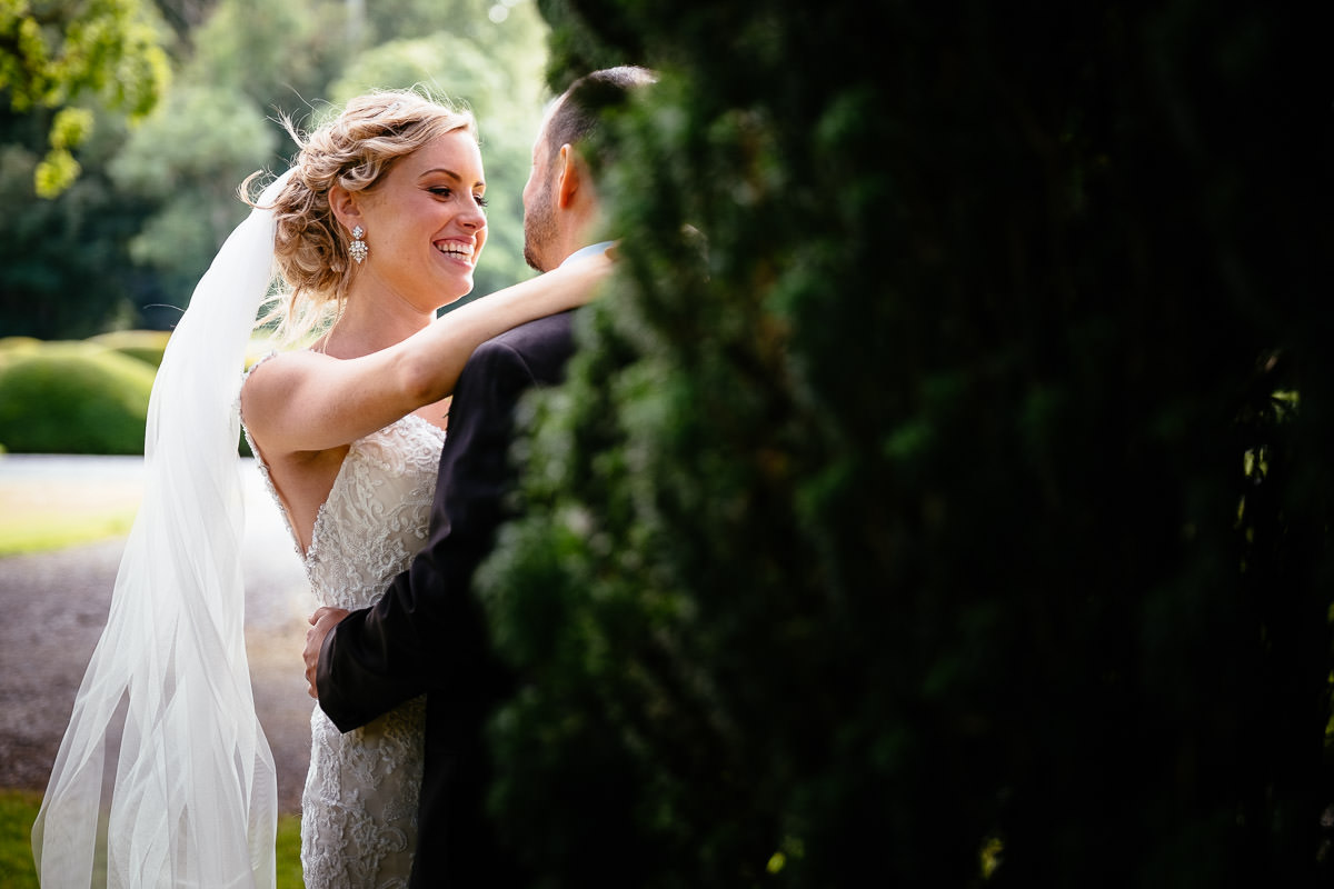 The bride laughs as the groom embraces her in the gardens at Carton House.
