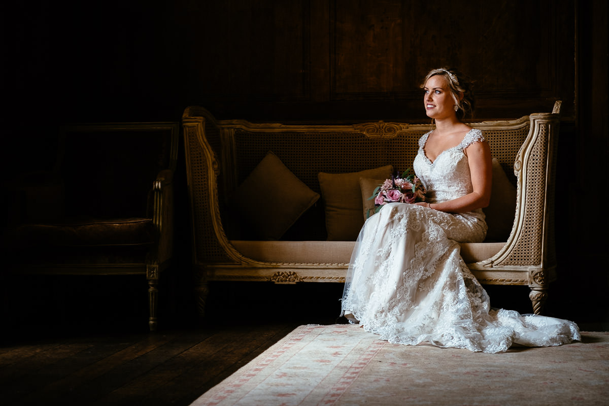 The bride sits alone on an antique sofa holding her bouquet at Carton House.