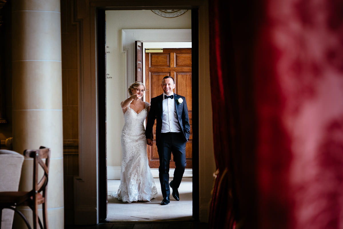 The bride points and laughs as she walks with the groom through a doorway at Carton House.