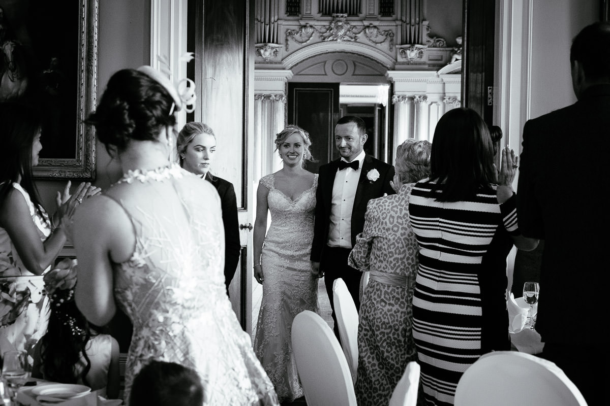 The bride and groom walk past clapping guests into the reception room at Carton House.