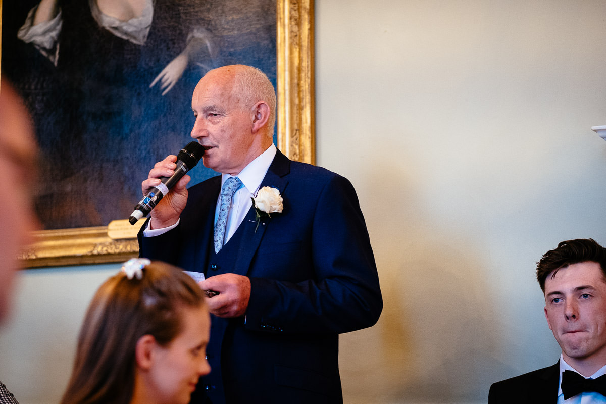 The bride's father gives a speech into a microphone during the reception at Carton House.