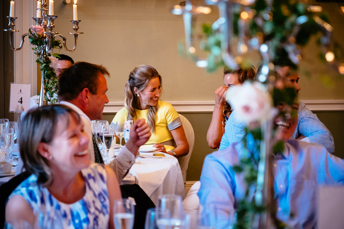 Guests laugh together at their table during the wedding speeches at Carton House.