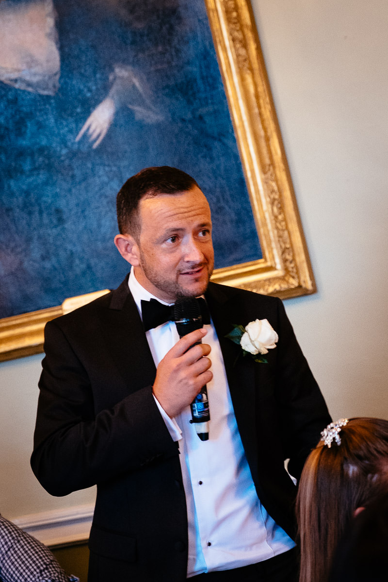 The groom gives a speech into a microphone during the wedding reception at Carton House.