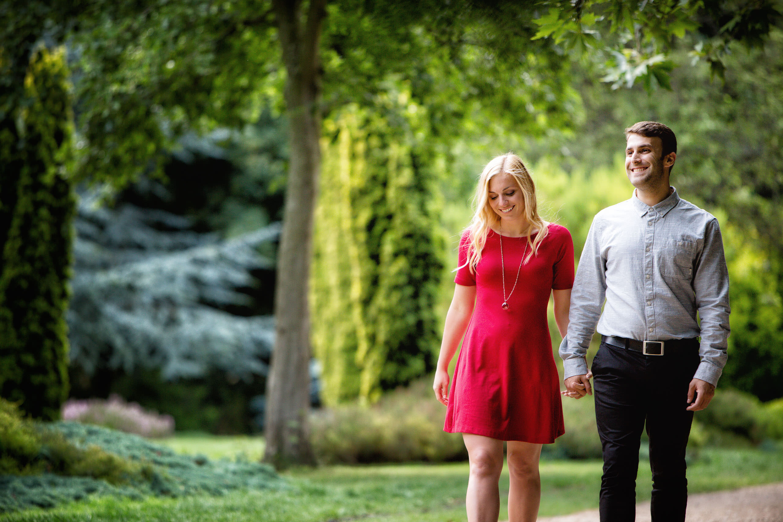 engaged couple walking hand in hand through Merrion Park in Dublin city
