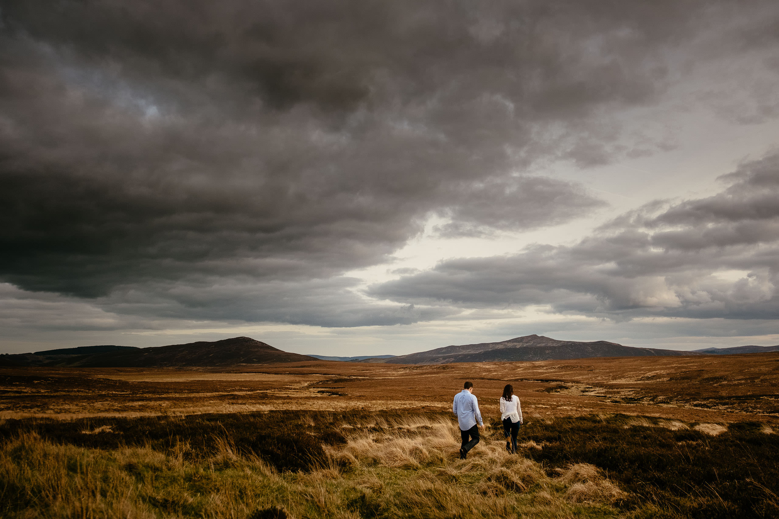 engaged couple walking holding hands in wicklow mountains