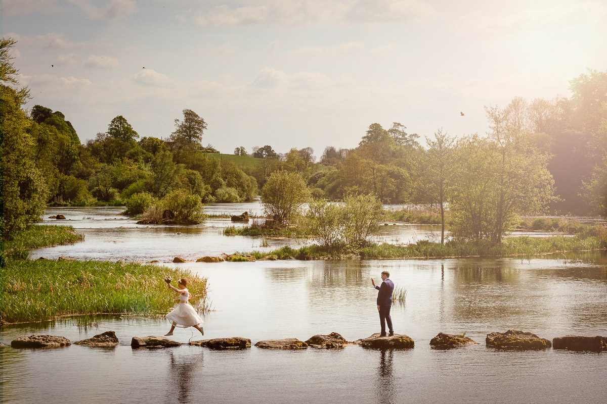 wedding photograph bride jumping over rocks across river