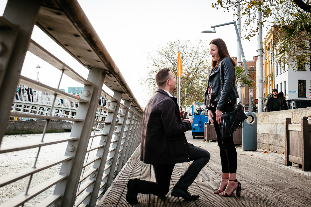 guy proposing to his girlfriend by the river liffey boardwalk in dublin