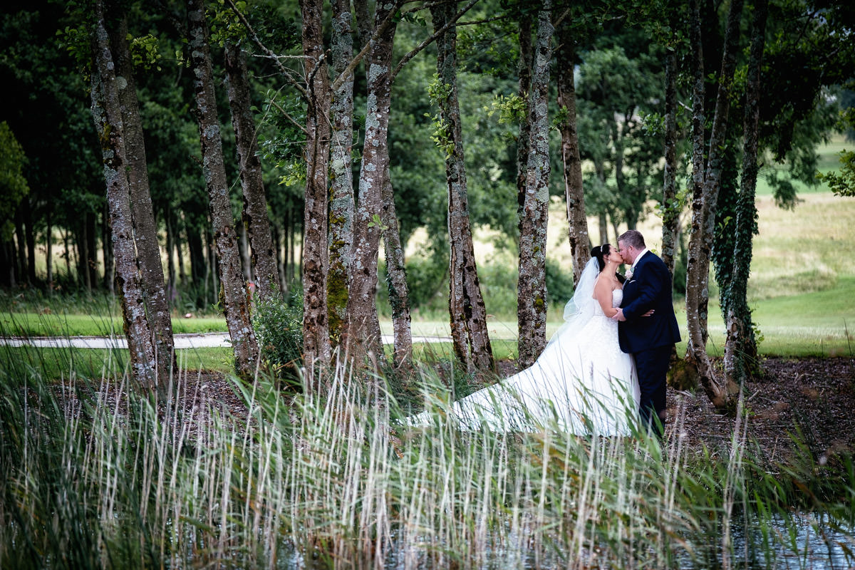 bride and groom kissing in the woods at glenlo abbey hotel wedding