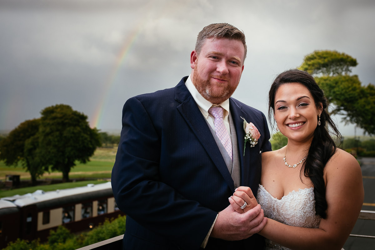 bride and groom at glenlo abbey hotel wedding with rainbow in the background