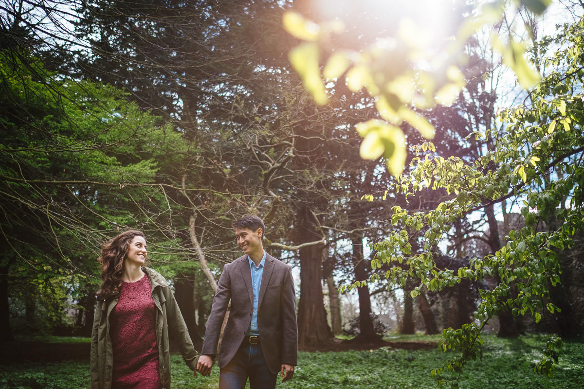 engaged couple looking at each other through filtered sunlight in st annes park