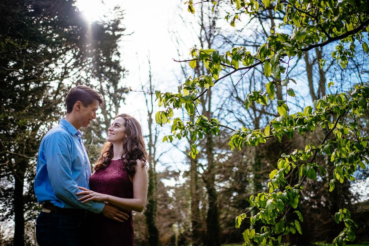 engaged couple embracing through filtered sunlight in st annes park
