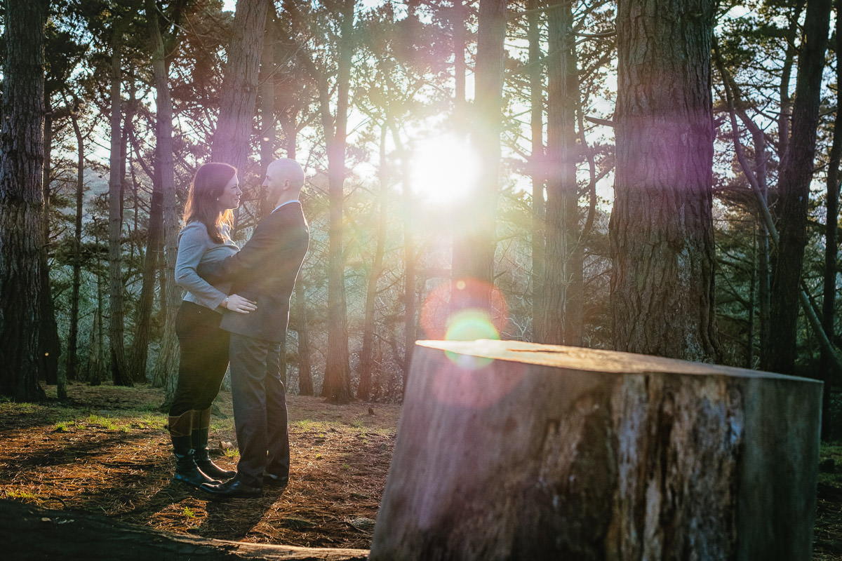 engaged couple in forest at sun set