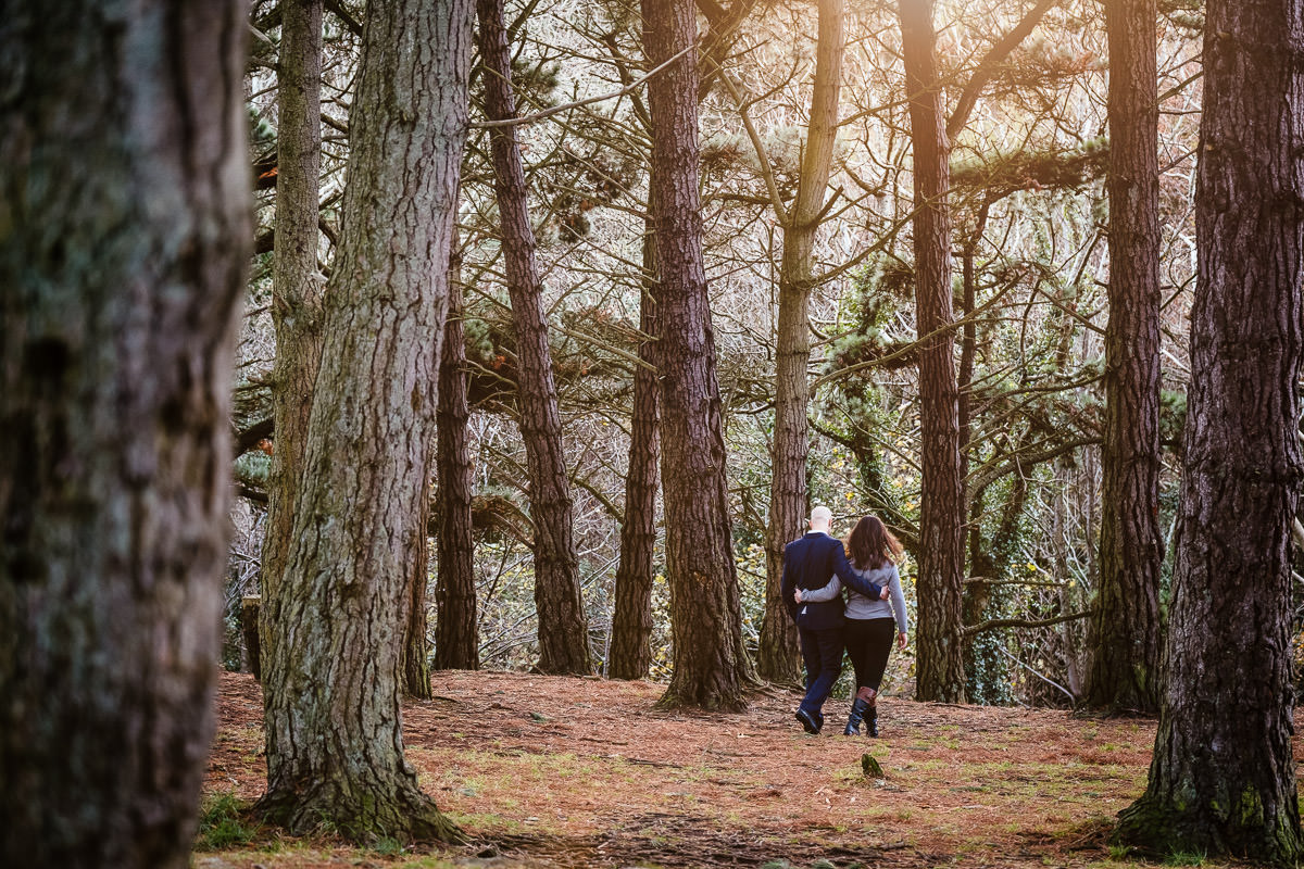 engaged couple walking in forest at sun set