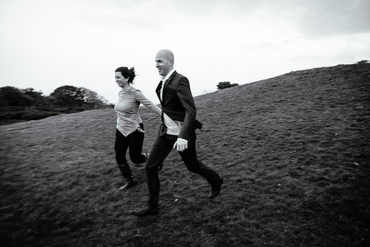 engaged couple running down a hill