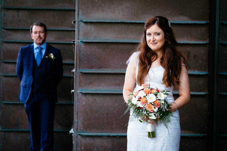 Stunning University College Cork Wedding 8 bride looking at camera with groom standing behind at university college cork wedding
