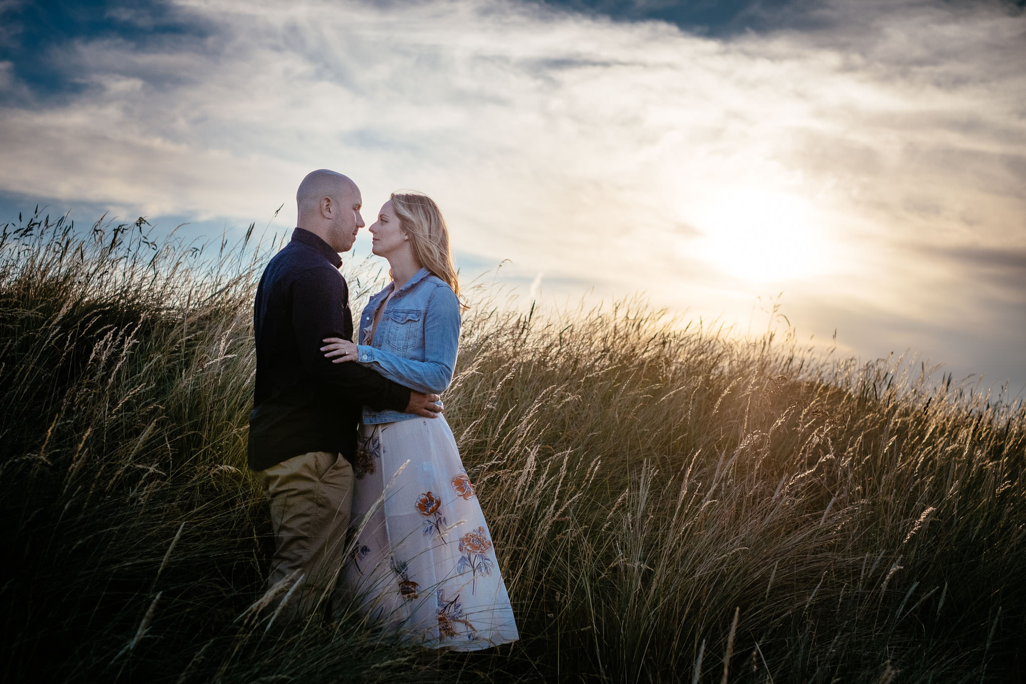 engaged couple in long grass at sunset in dublin