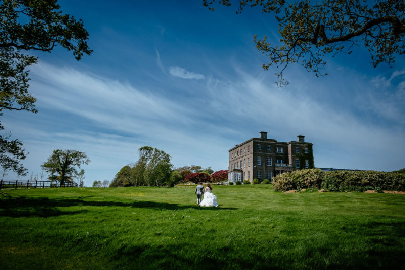 bride and groom walking through field in fron of horetown house in wexford