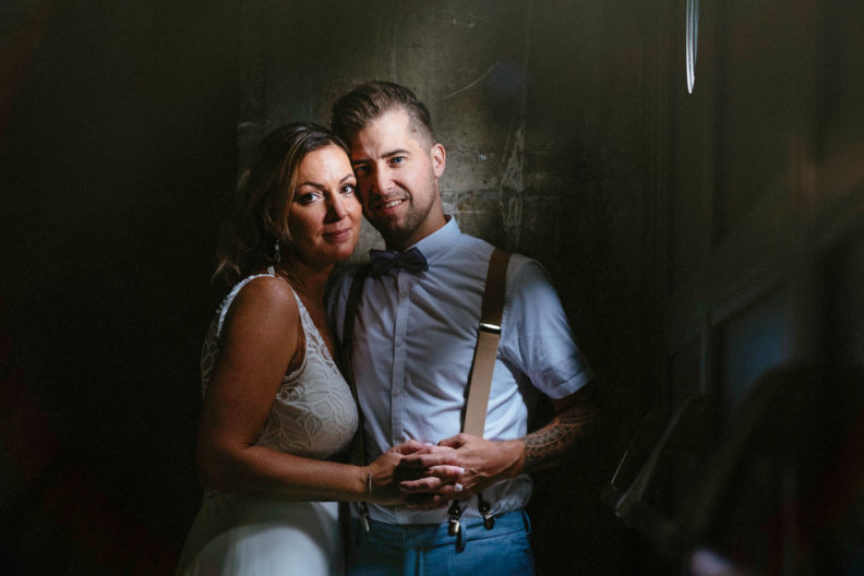 A bride and groom posing for a photo in a dark room during their destination wedding.