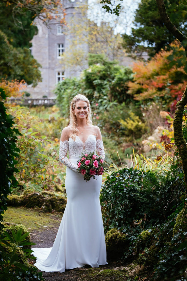 full length shot of bride in garden holding flowers