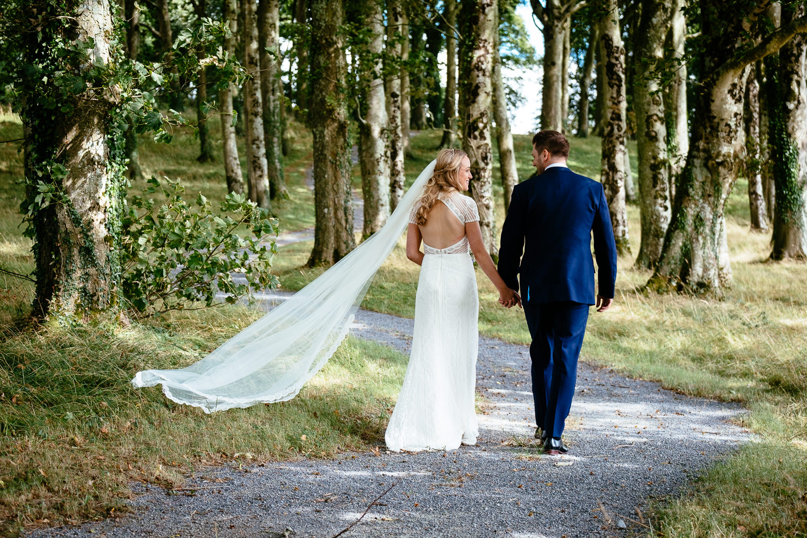 bride and groom walking through woods