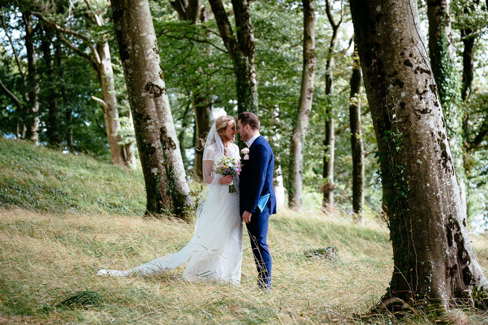 bride and groom walking through woods