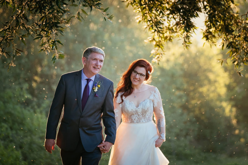 bride and groom walking through forest at sunset during their cabra castle wedding