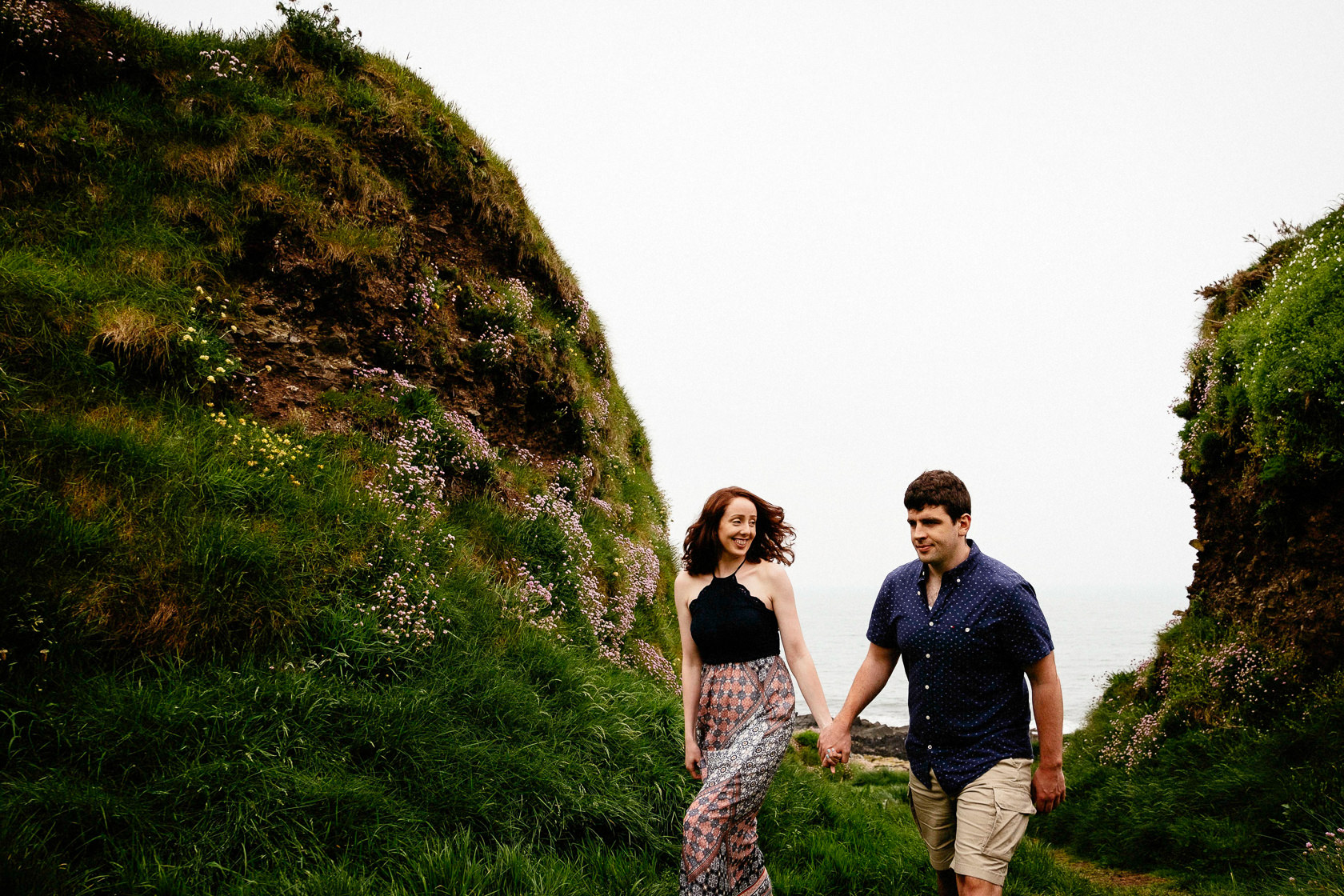 engaged couple walking along a beach in ballycotton county cork ireland
