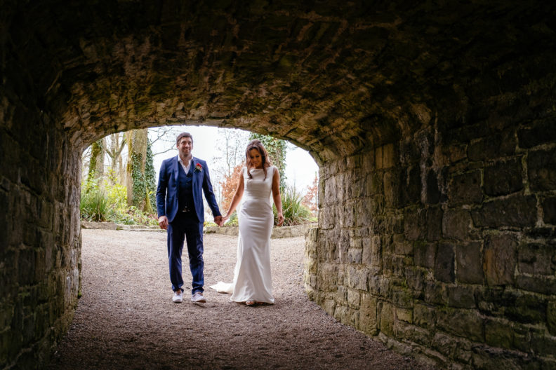 Lovely Winter-time Clonabreany House Wedding 6 bride and groom walking under an arch holding hands