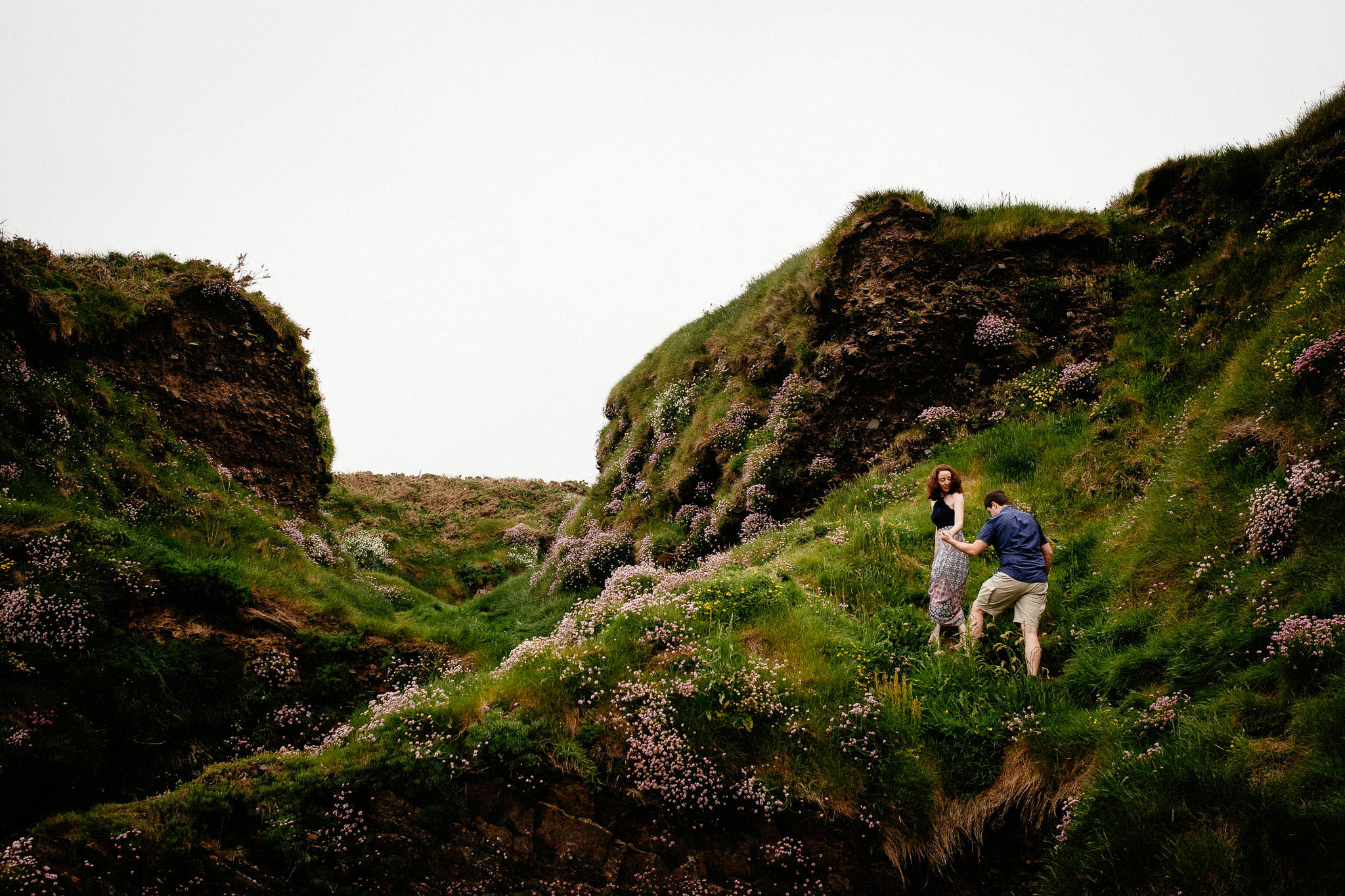 newly engaged couple climbing a cliff in ballycotton cork ireland
