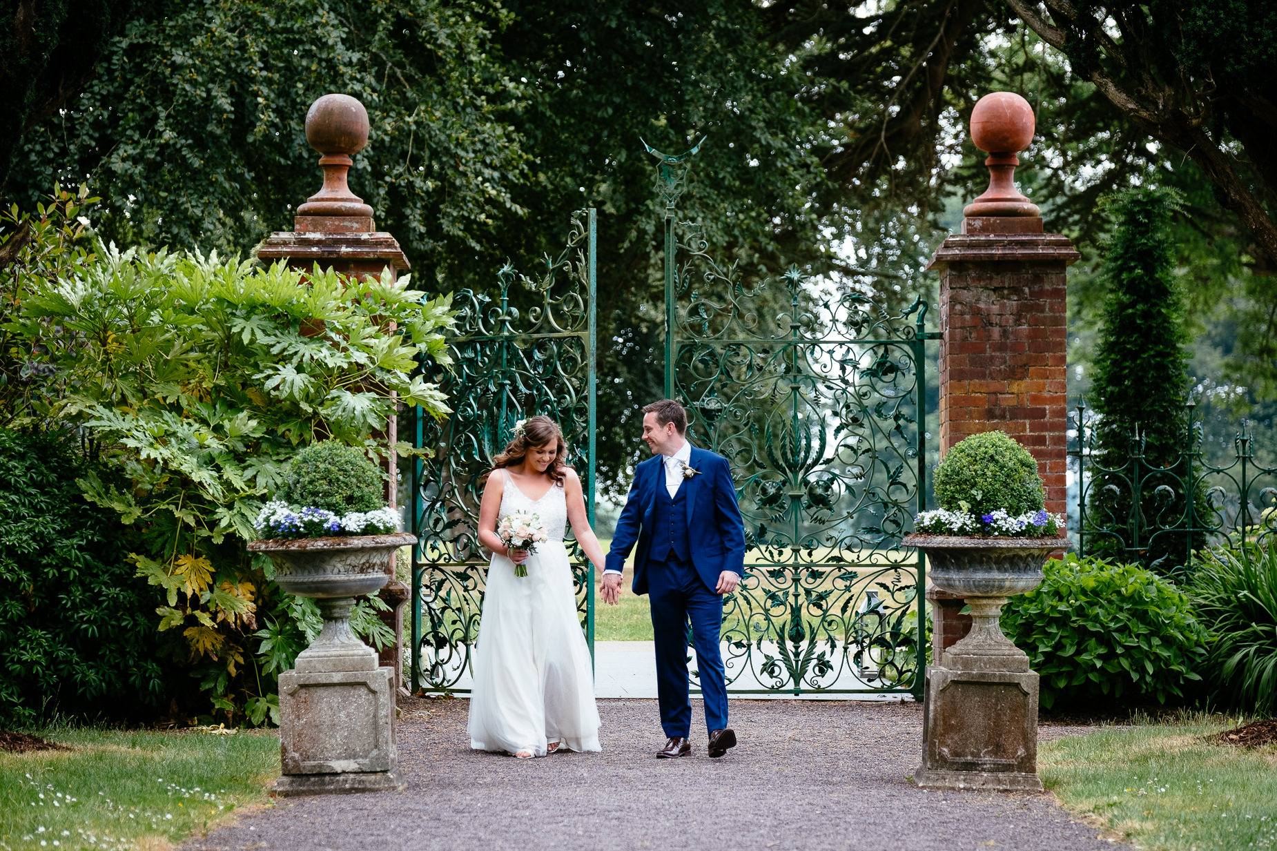 bride and groom walking in a walled garden