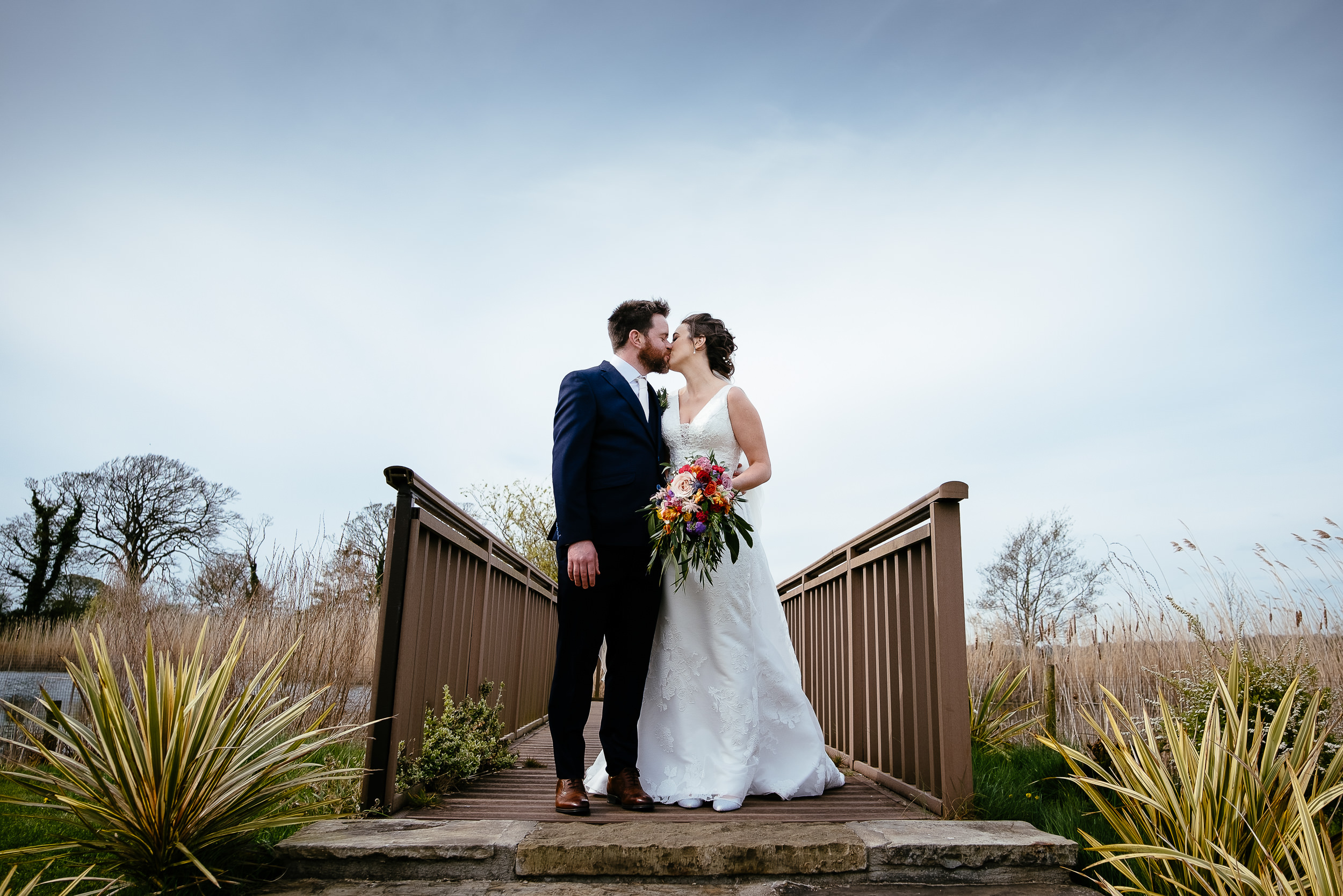 bride and groom standing on a jetty kissing at Ballymagarvey village meath