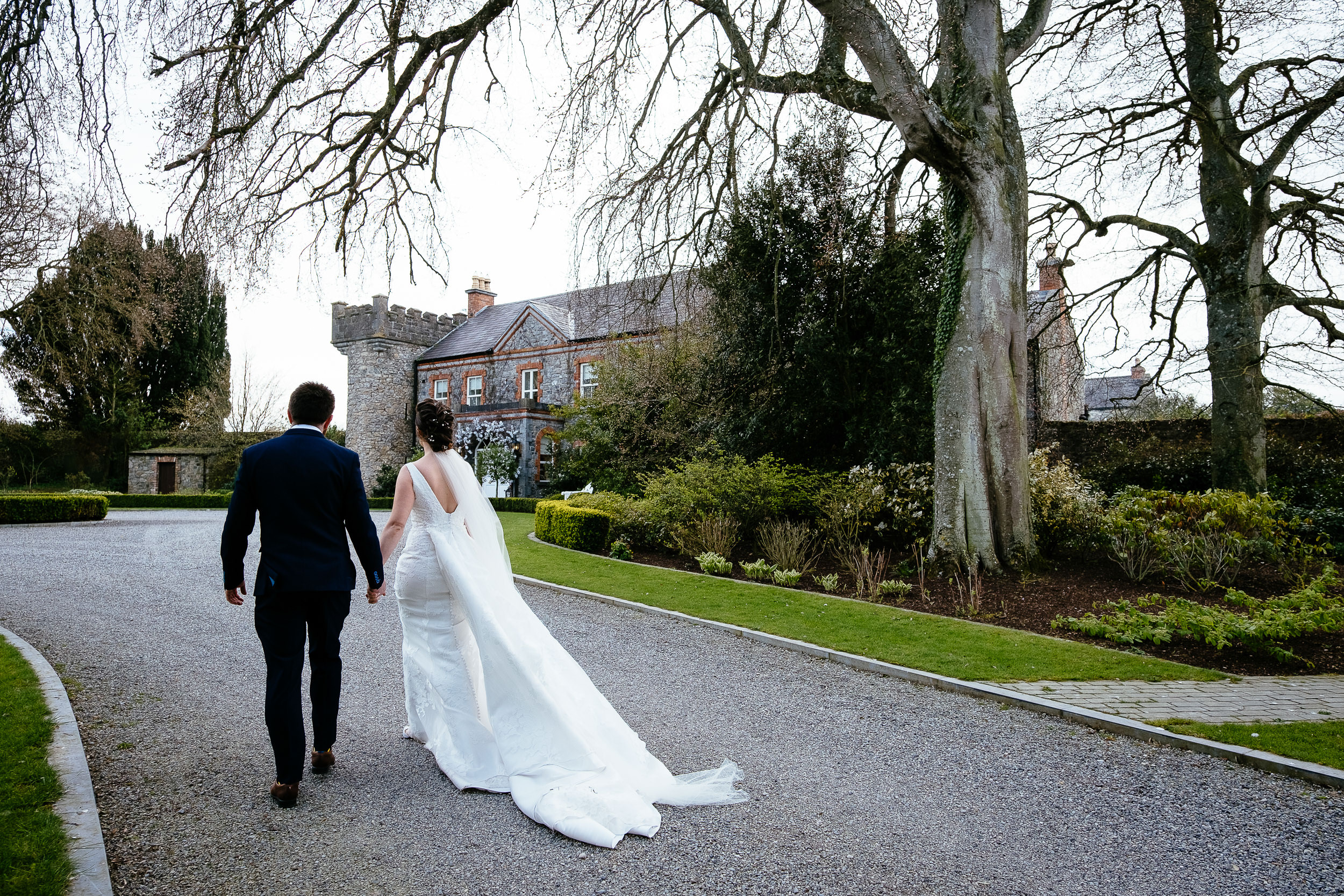 bride and groom walking towards a house