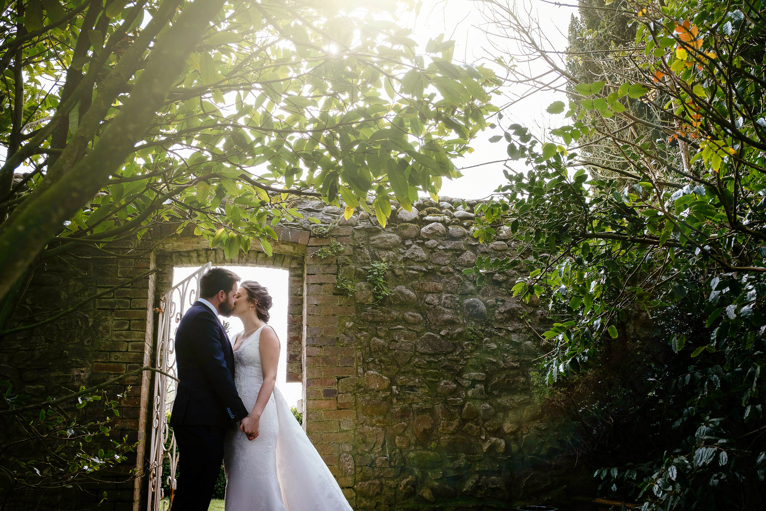 bride and groom embracing in front of doorway with sun setting behind