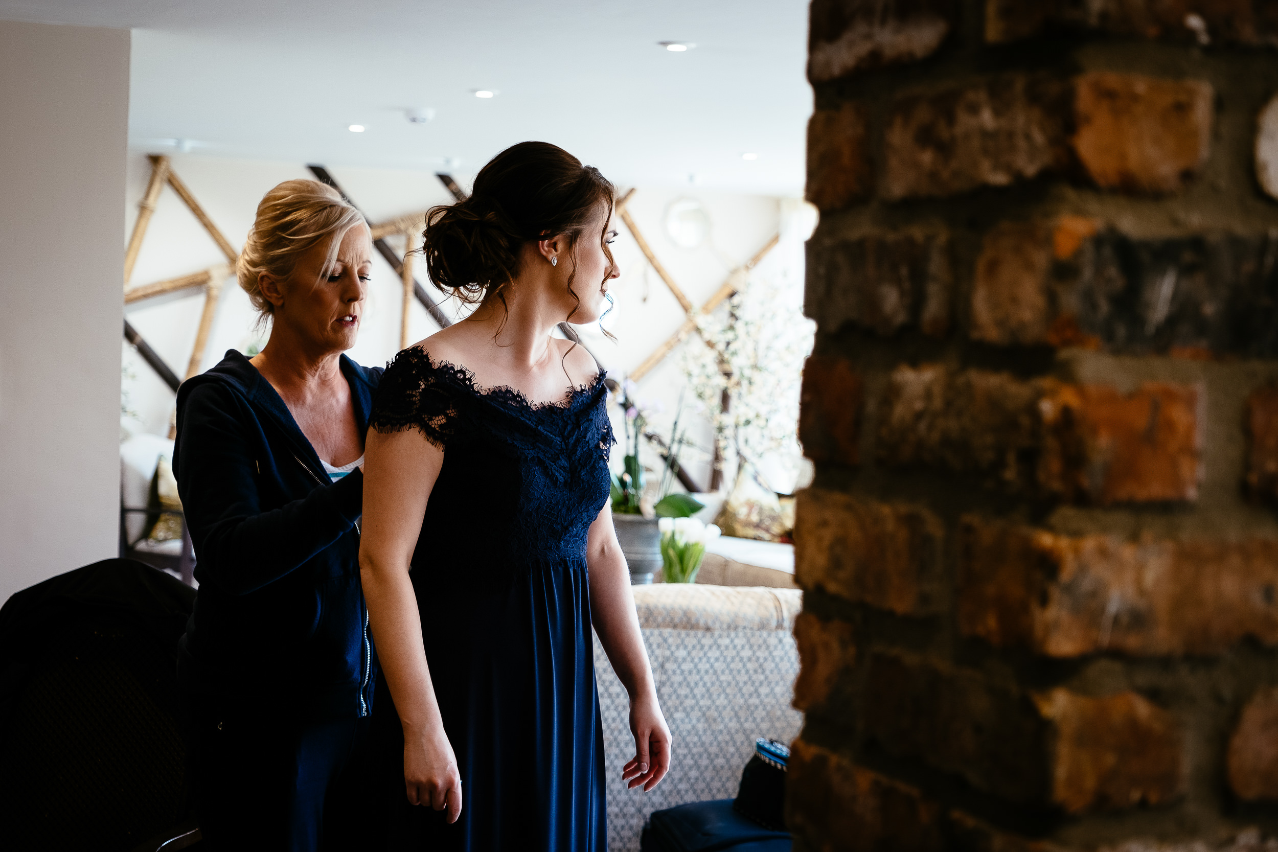 bridesmaid having her dress buttoned up