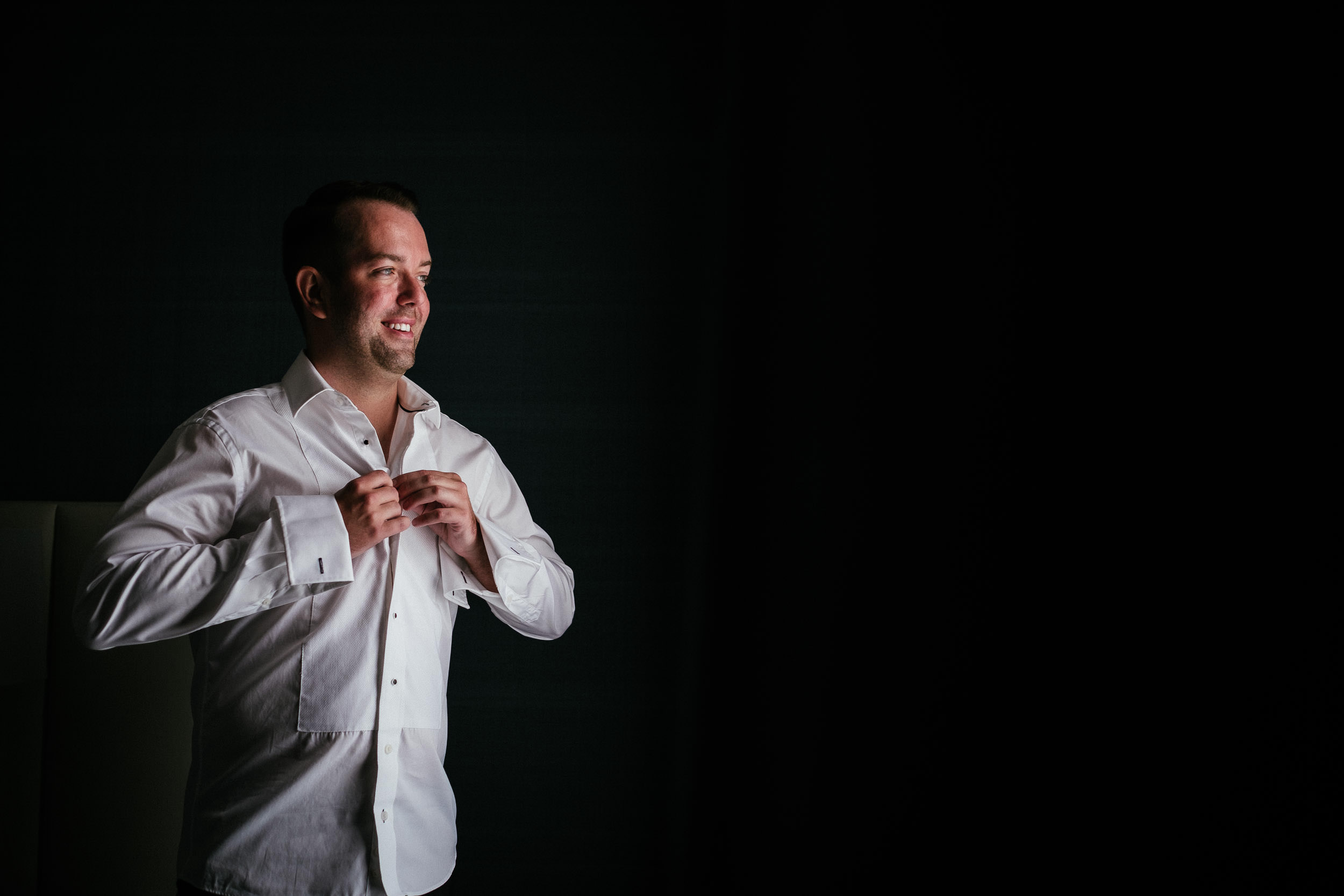 groom buttoning shirt at Johnstown House estate