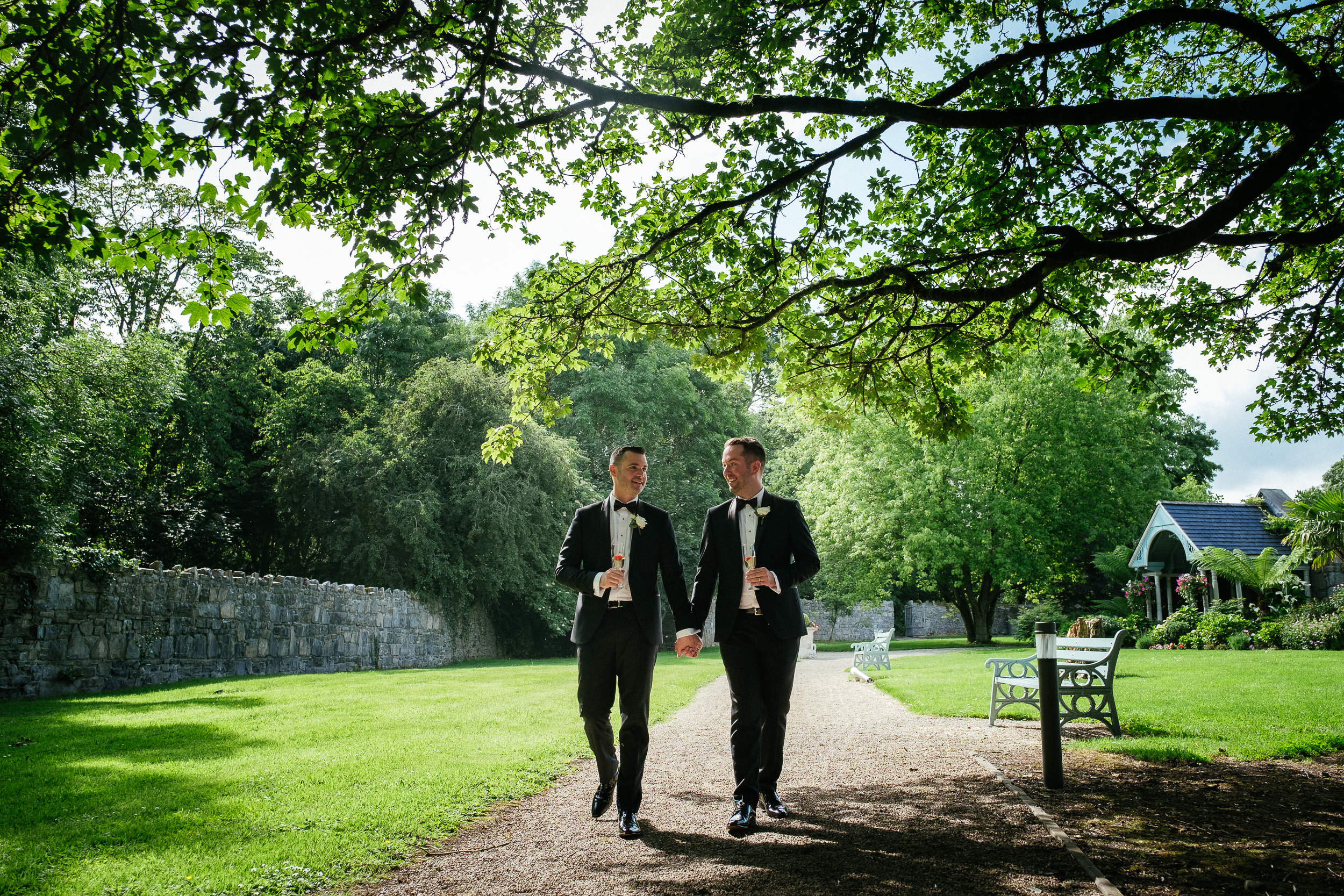 gay grooms walking hand in hand at Johnstown House estate
