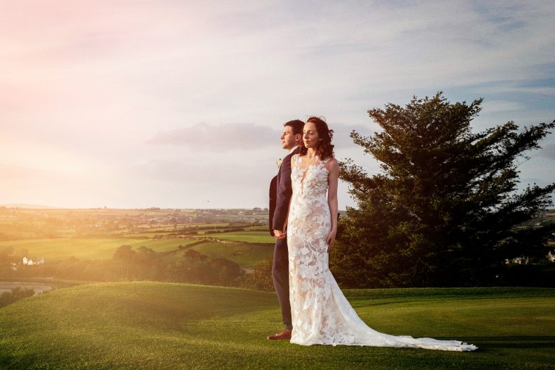 Bride and groom standing looking into the setting sun at their Clonakilty Cork Wedding