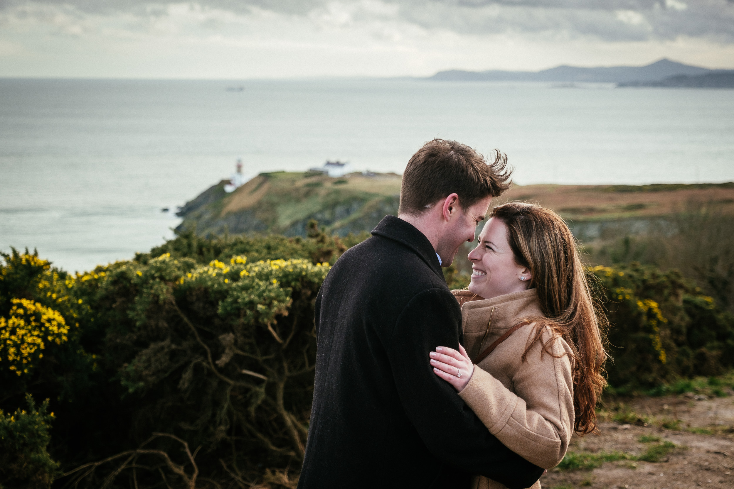engaged couple laughing on the cliff path at howth summit dublin