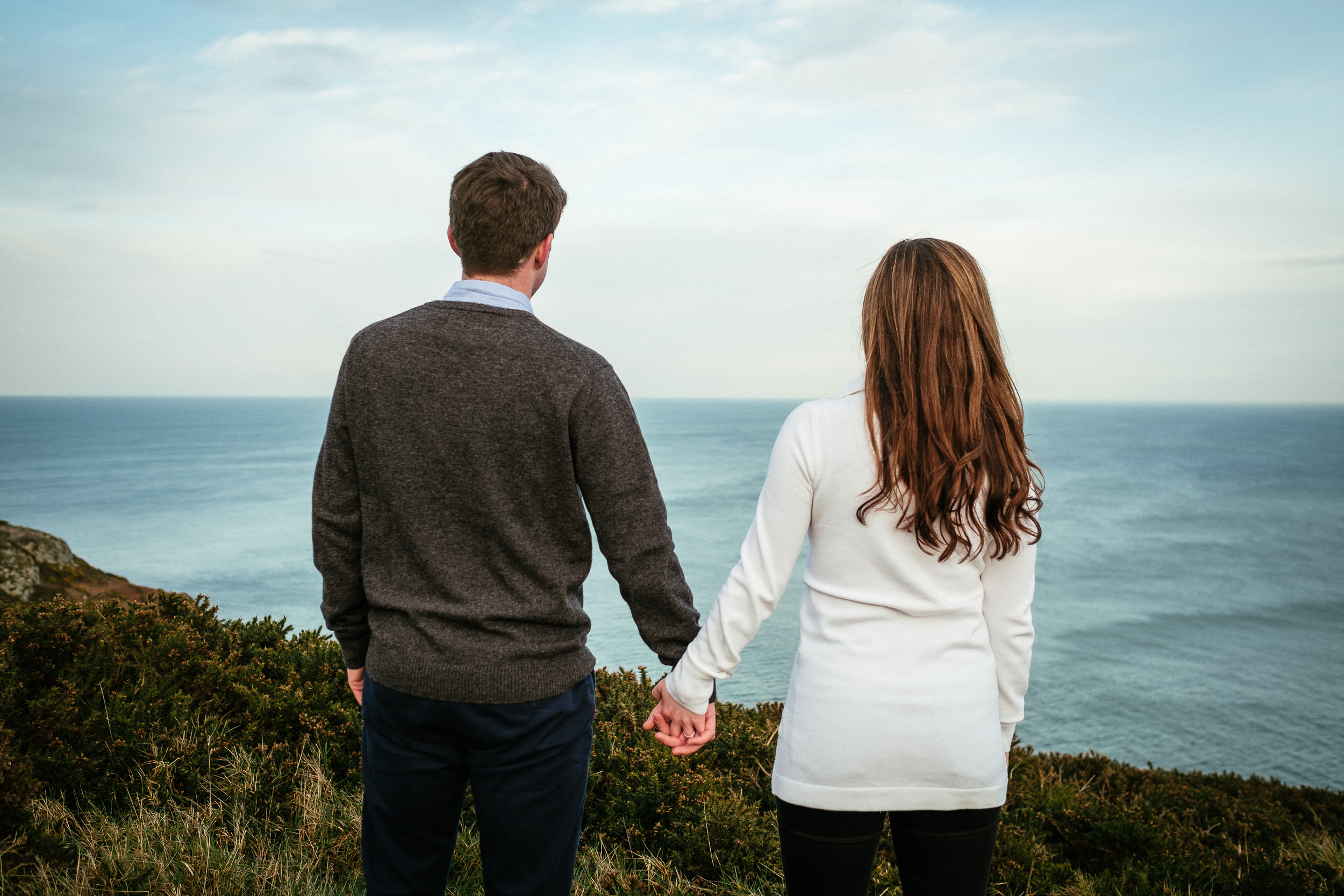 couple holding hands looking out onto the Irish Sea after proposing at Howth Head Dublin