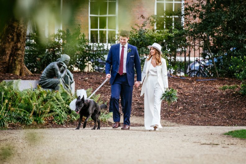 bride and groom walking their dog through Merrion Park Dublin after their Dublin registry office wedding