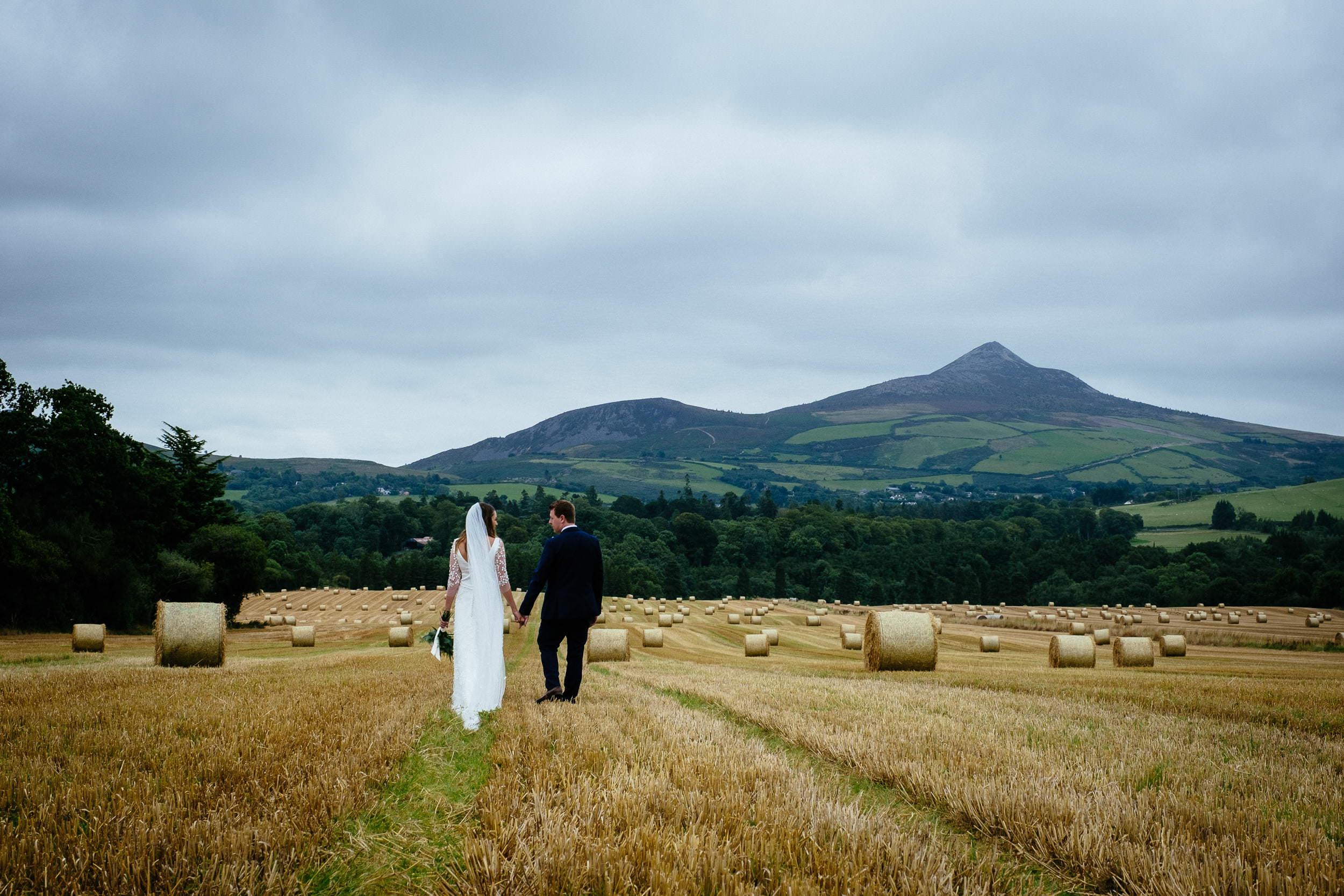 bride and groom on the river walk after their powerscourt wedding with the sugar loaf in the background