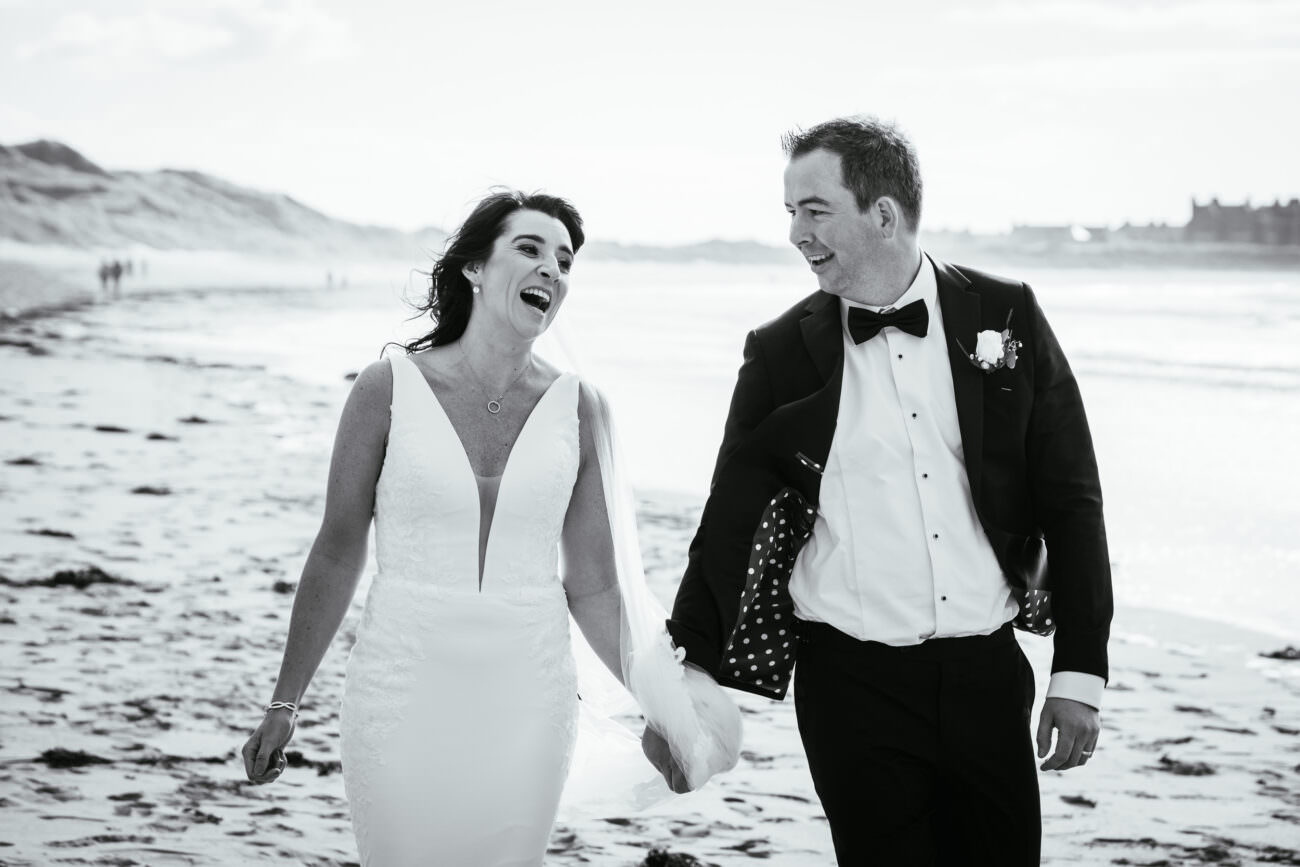 bride laughing on beach with Trump International Hotel Doonbeg in the background